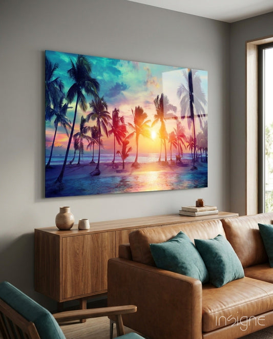 Tropical sunset glass art hanging above wooden cabinet in modern living room with leather sofa and teal pillows.