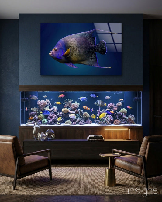 Modern living room with a mounted display screen showing a Queen Angelfish above a saltwater aquarium tank with colorful coral and fish.