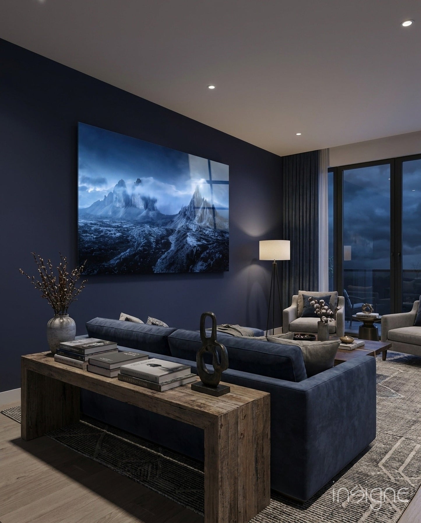 Blue mountain landscape glass art displayed on dark wall above navy sofa in modern living room.