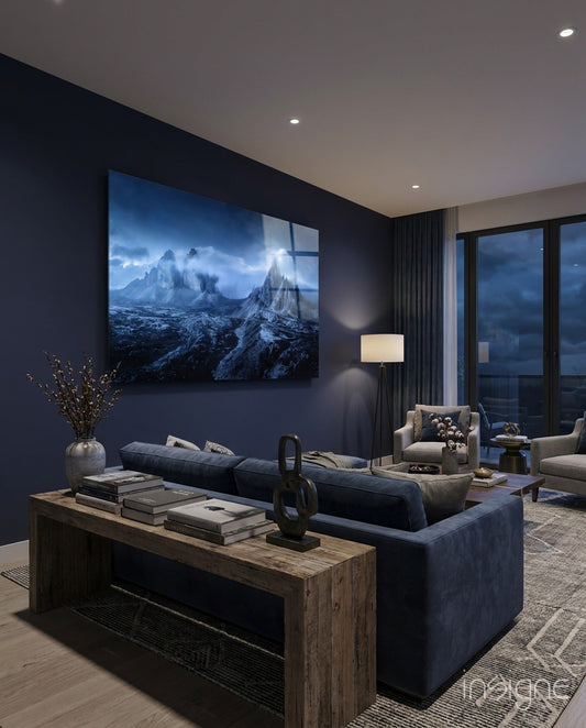 Blue mountain landscape glass art displayed on dark wall above navy sofa in modern living room.
