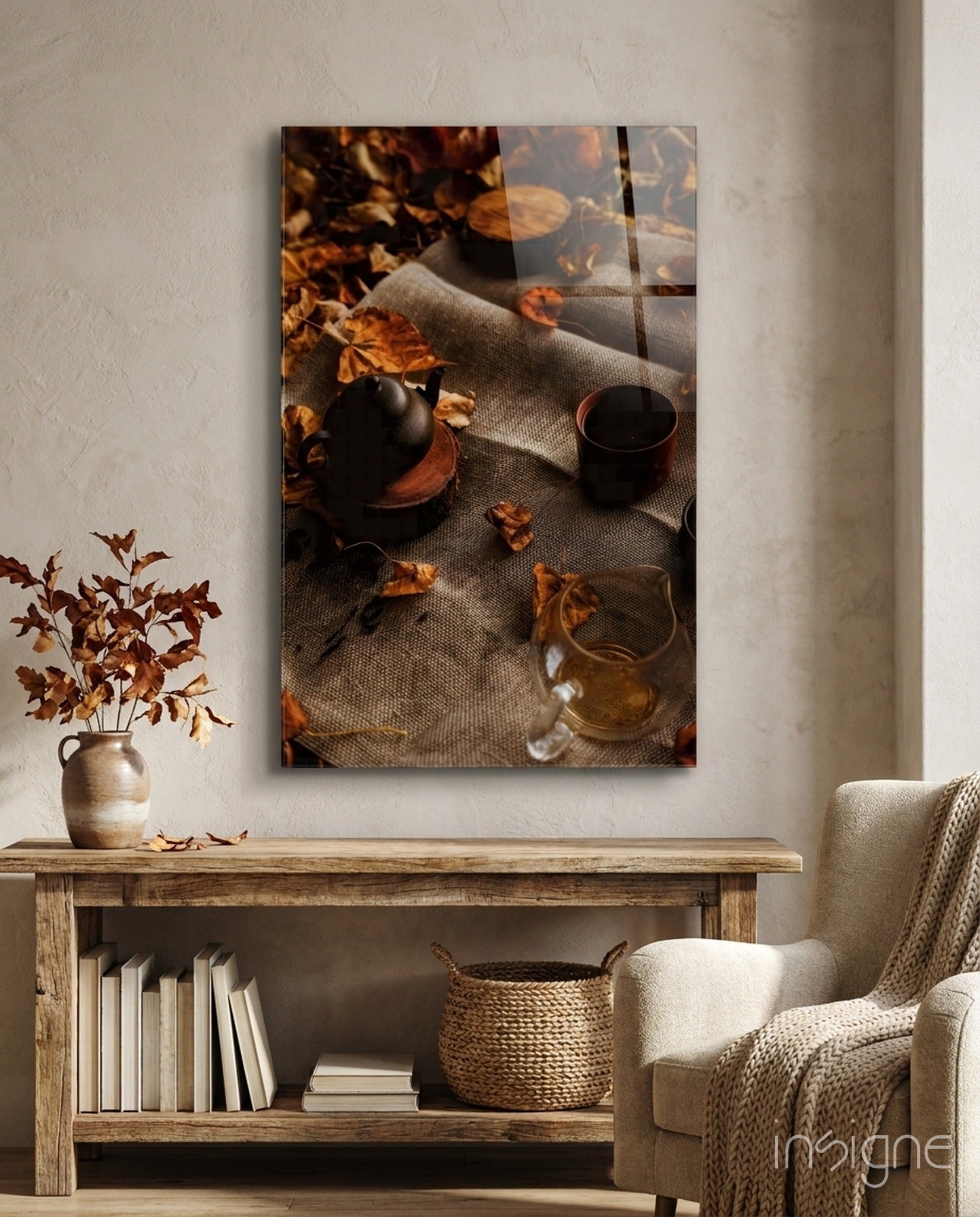 Autumn Picnic glass art displayed on white wall above wooden shelf, showing teapot, cup, dried leaves, and fabric on neutral background.