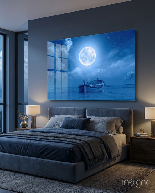 Moon and Boat Glass Wall Art displayed above a bed in a modern bedroom with blue tones and illuminated bedside lamps.
