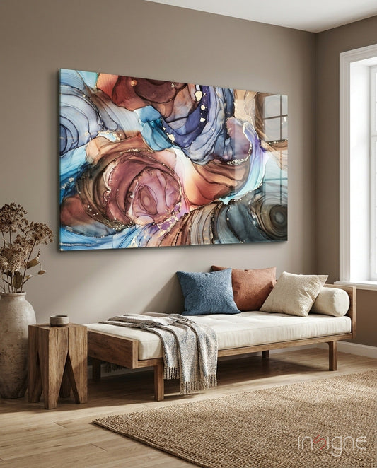 Abstract swirled copper, blue, and pink ink marble glass art hung above a wooden daybed with cream cushions and colored pillows in a neutral room.