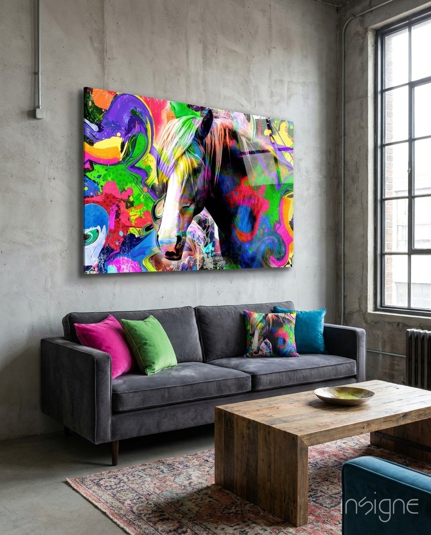Vibrant multicolored horse glass wall art displayed above gray sofa in industrial loft setting with concrete walls.