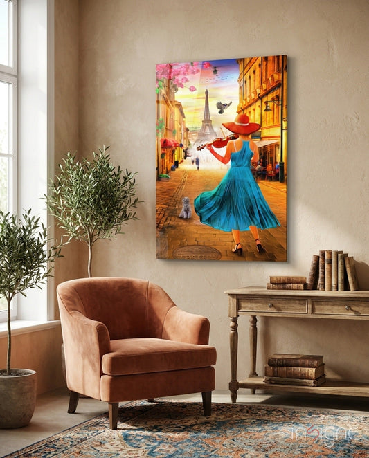 Colorful glass wall art depicting a woman in blue dress playing violin on a Paris street with Eiffel Tower, displayed above a terracotta armchair in a home interior.