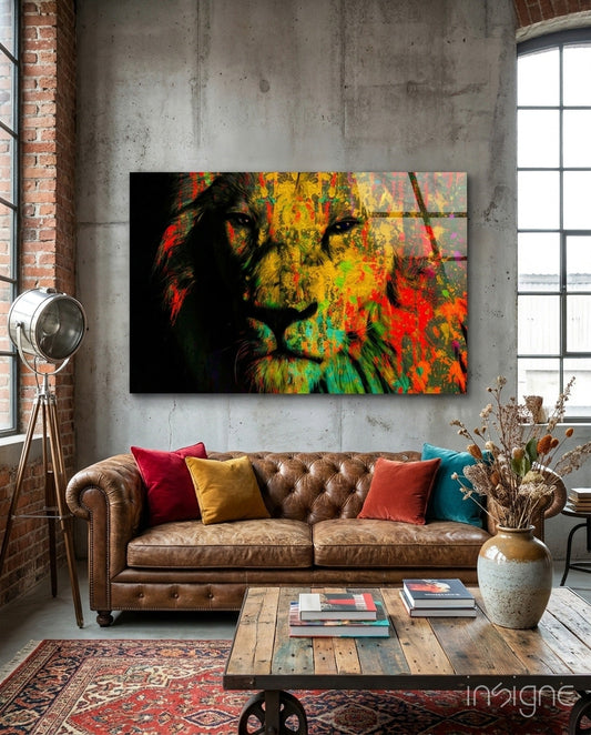 Colorful lion head glass wall art with yellow, red, green, and orange paint splotches displayed above a brown leather sofa in an industrial loft.