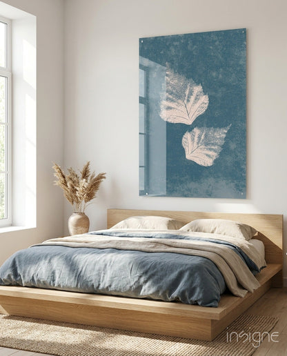 Teal glass wall art with two white leaf prints mounted above wooden bed in minimalist bedroom.
