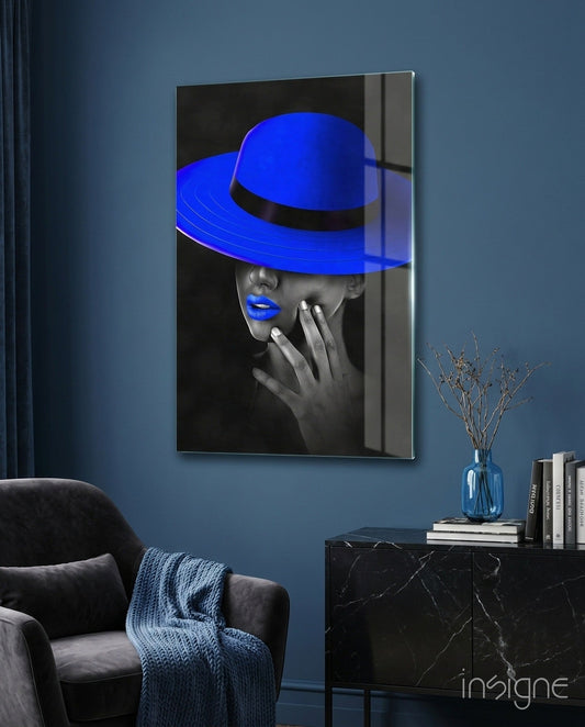 Blue Hat Glass Wall Art displayed on blue bedroom wall above black marble nightstand with books and vase.