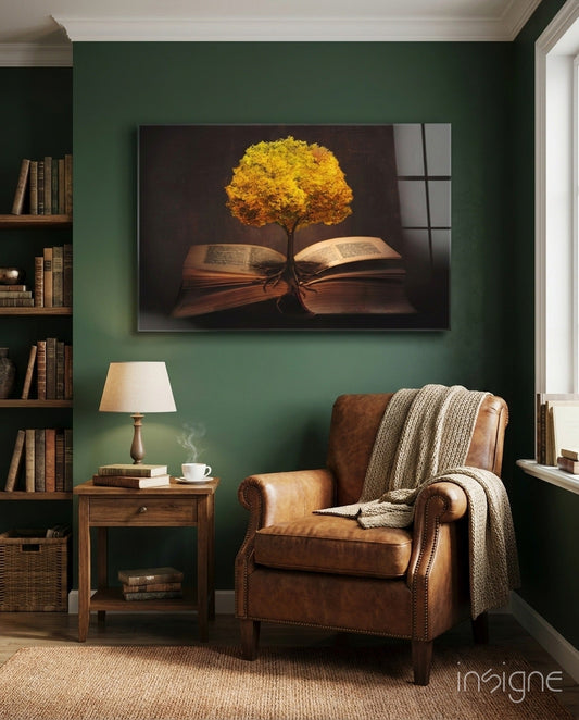Glass wall art featuring golden tree growing from open book pages displayed above brown leather armchair in green study room.