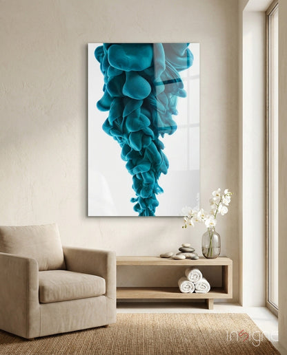 Blue layered glass wall art depicting cascading turquoise ink clouds displayed above wooden shelf in minimalist room setting.