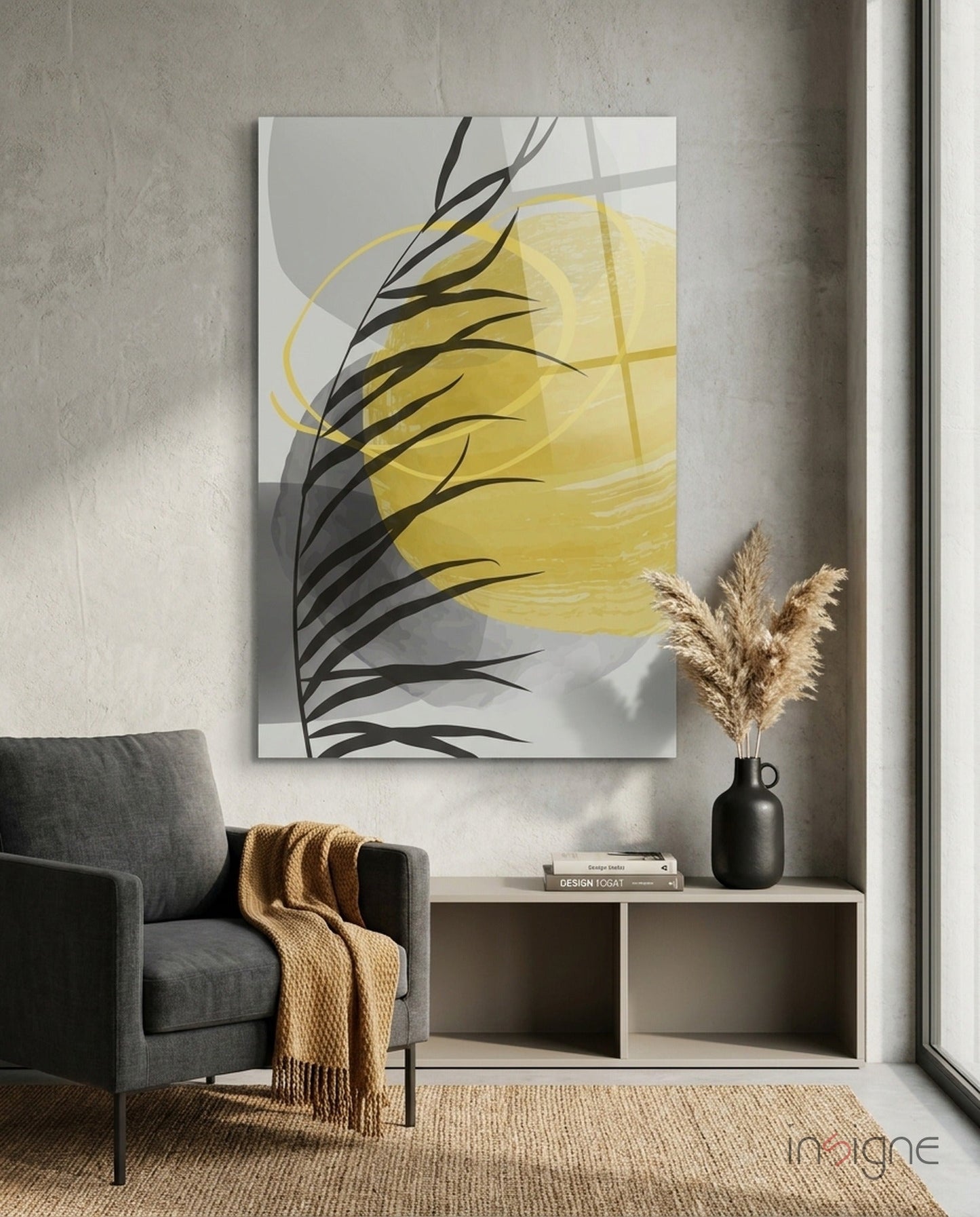 Modern interior setting featuring yellow and black abstract glass wall art above white shelving, with gray armchair and pampas grass decor.