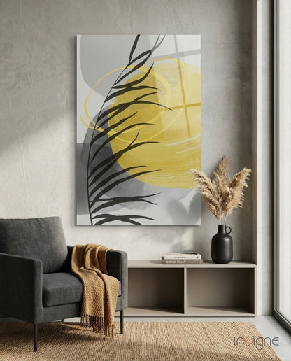 Modern interior setting featuring yellow and black abstract glass wall art above white shelving, with gray armchair and pampas grass decor.
