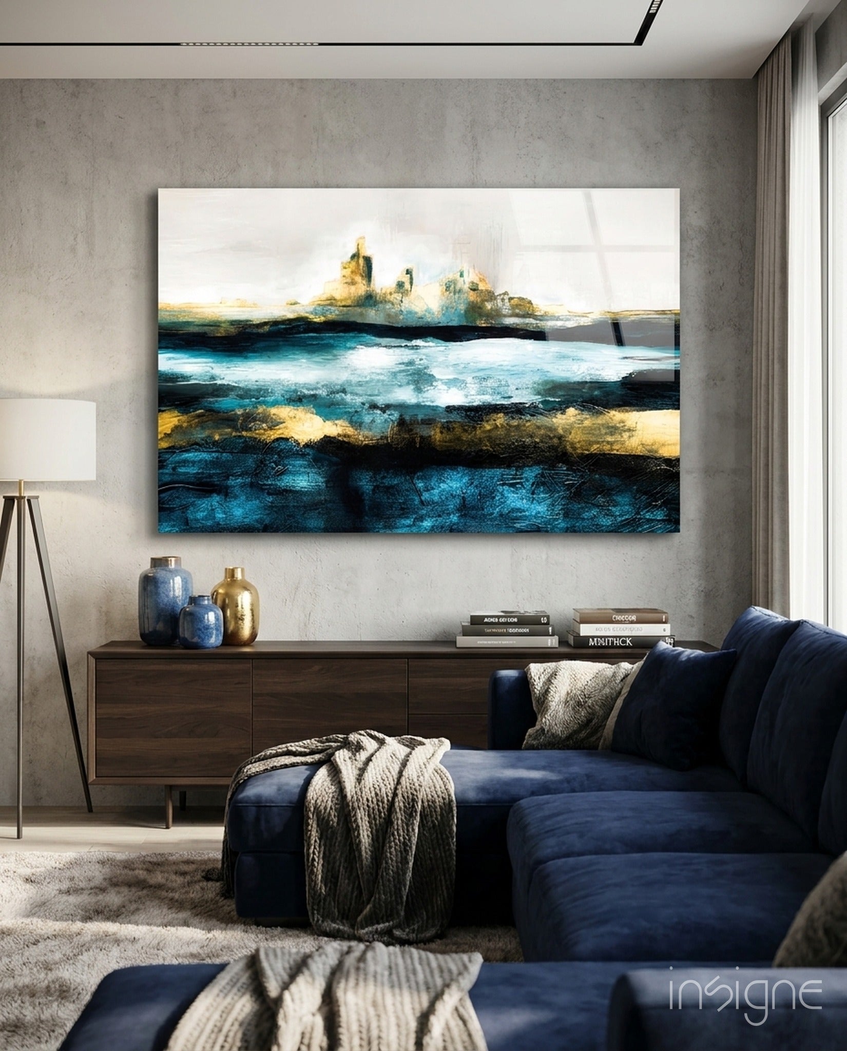 Abstract glass wall art with layered blue, gold, and white horizontal bands depicting a seascape, displayed above dark wood console in modern living room.