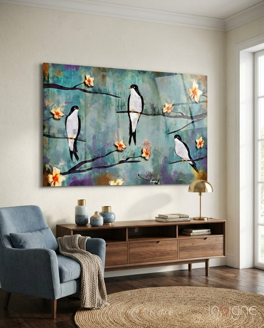 Glass wall art depicting black and white birds perched on branches with yellow flowers against a turquoise, purple, and gold textured background, displayed above a wooden console table in a living room.