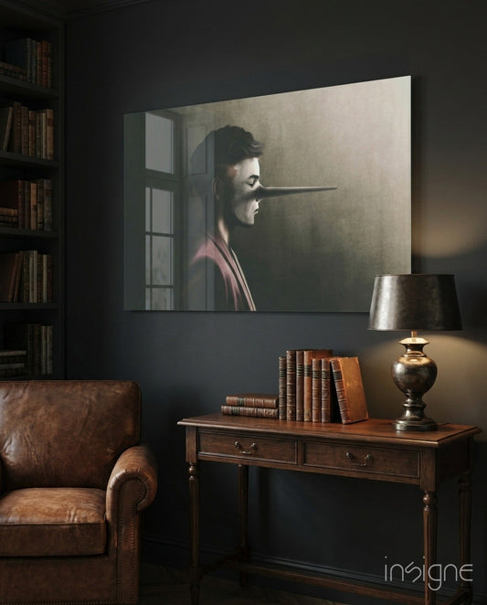 Glass wall art depicting a profile of a man with an elongated nose against a neutral background, displayed above a wooden desk in a dark study room.