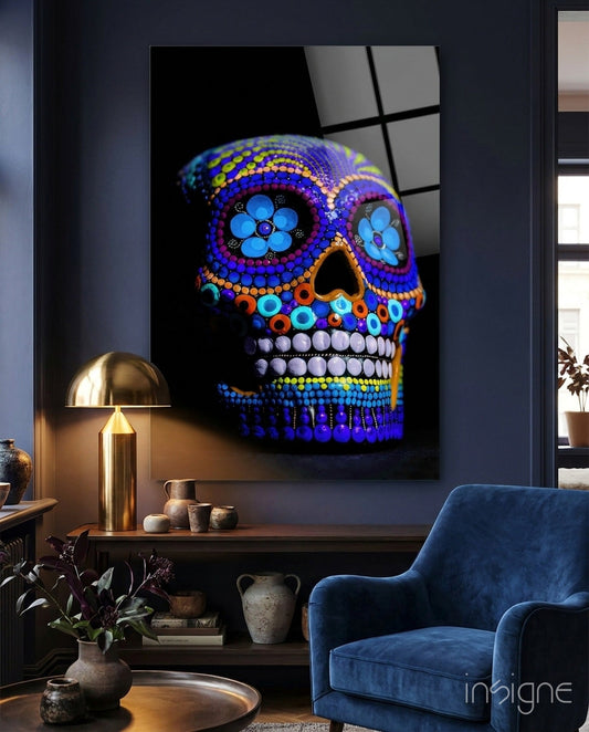 Cobalt blue beaded sugar skull glass wall art displayed above a console table in a modern living room setting with brass lamp and blue chair.