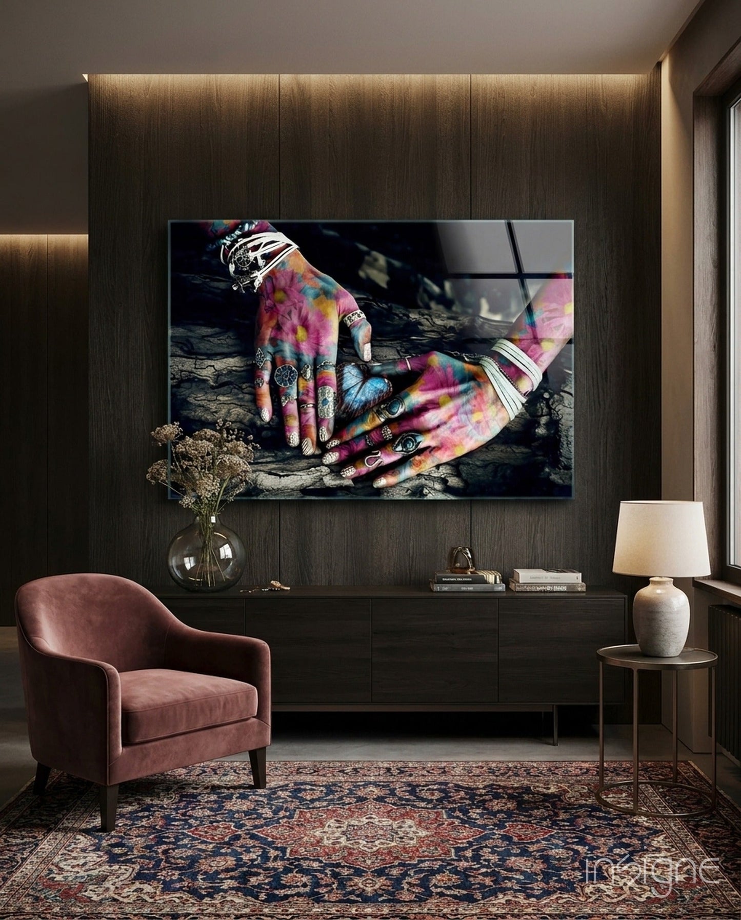 Colorful hands with vibrant tie-dye patterns and silver rings displayed on dark wooden wall art in modern living room setting.