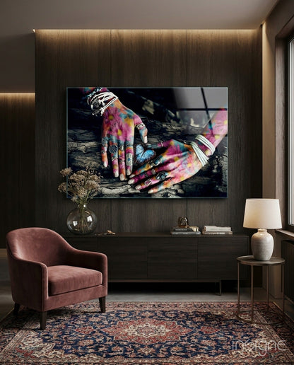 Colorful hands with vibrant tie-dye patterns and silver rings displayed on dark wooden wall art in modern living room setting.