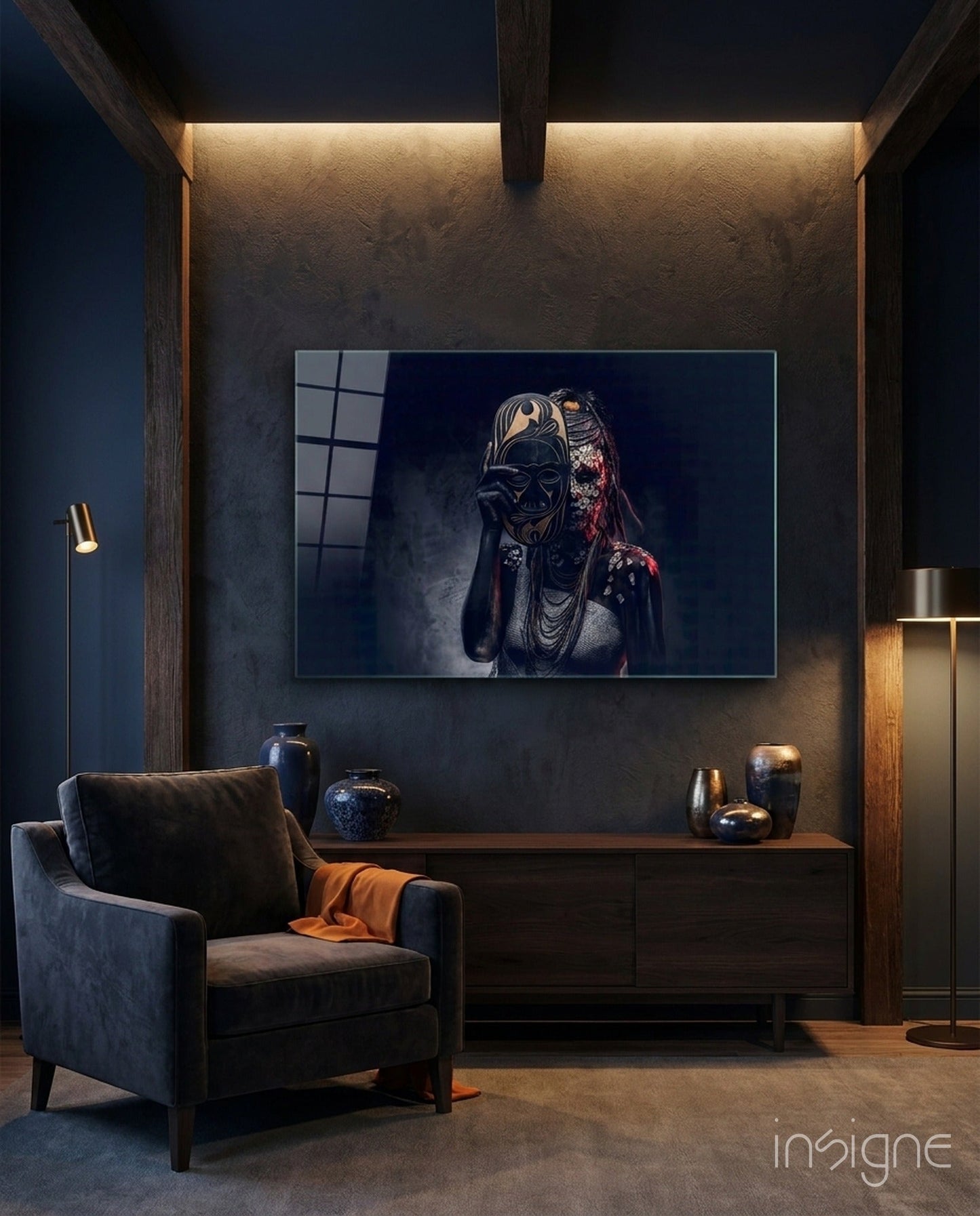 Behind the Mask glass wall art displayed above a wooden console in a modern dark interior with accent lighting.