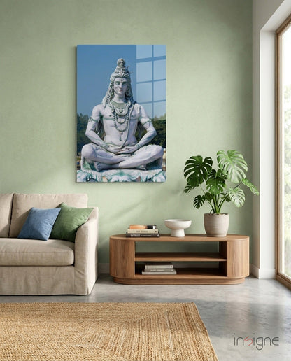 Glass wall art depicting Shiva in meditation pose displayed above wooden console table in sage green living room interior.