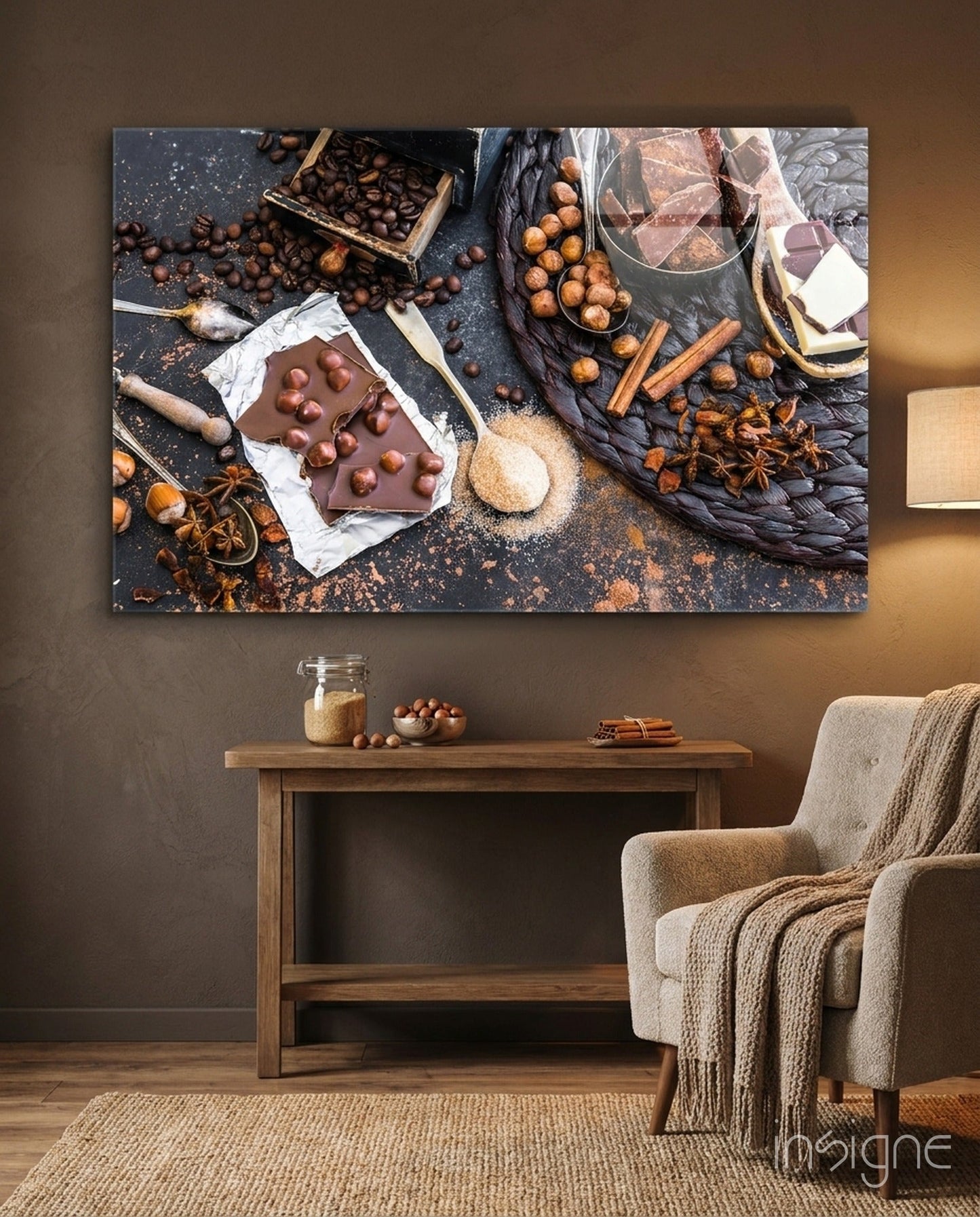 Chocolate glass wall art displaying chocolate bar with hazelnuts surrounded by cocoa beans, cinnamon sticks, and spices on dark surface, installed above wooden console table.