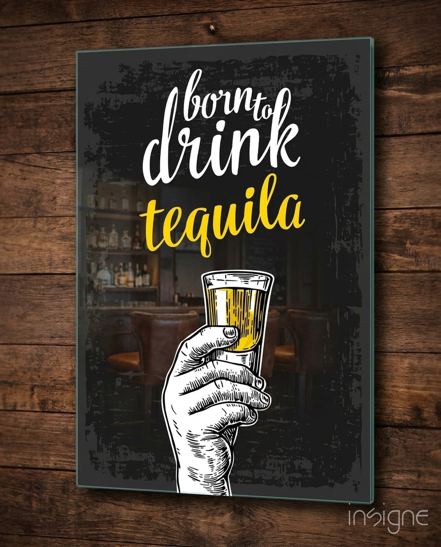 Black glass wall art with white and yellow text reading "born to drink tequila" and an illustrated hand holding a tequila shot glass, mounted on wooden wall.