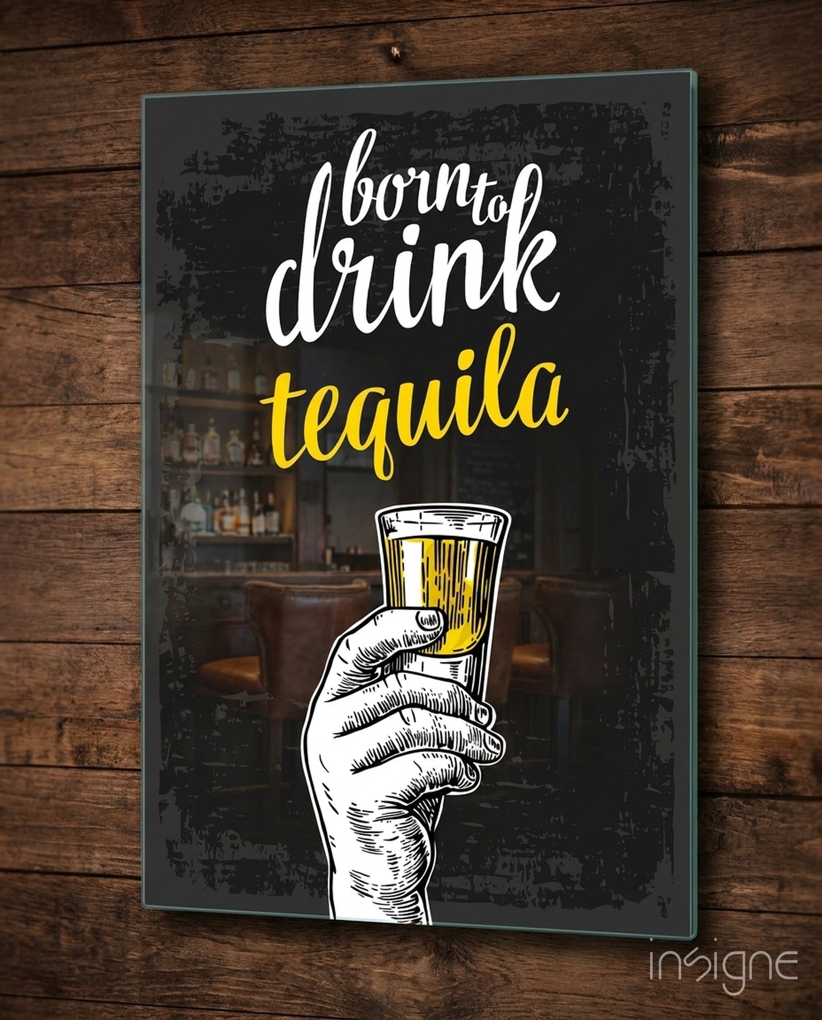 Black glass wall art with white and yellow text reading "born to drink tequila" and an illustrated hand holding a tequila shot glass, mounted on wooden wall.
