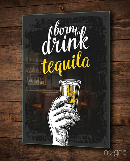 Black glass wall art with white and yellow text reading "born to drink tequila" and an illustrated hand holding a tequila shot glass, mounted on wooden wall.