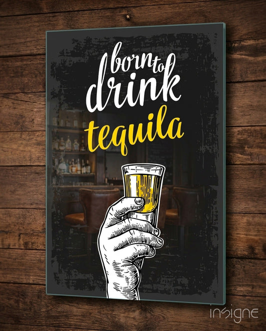 Black glass wall art with white and yellow text reading "born to drink tequila" and an illustrated hand holding a tequila shot glass, mounted on wooden wall.
