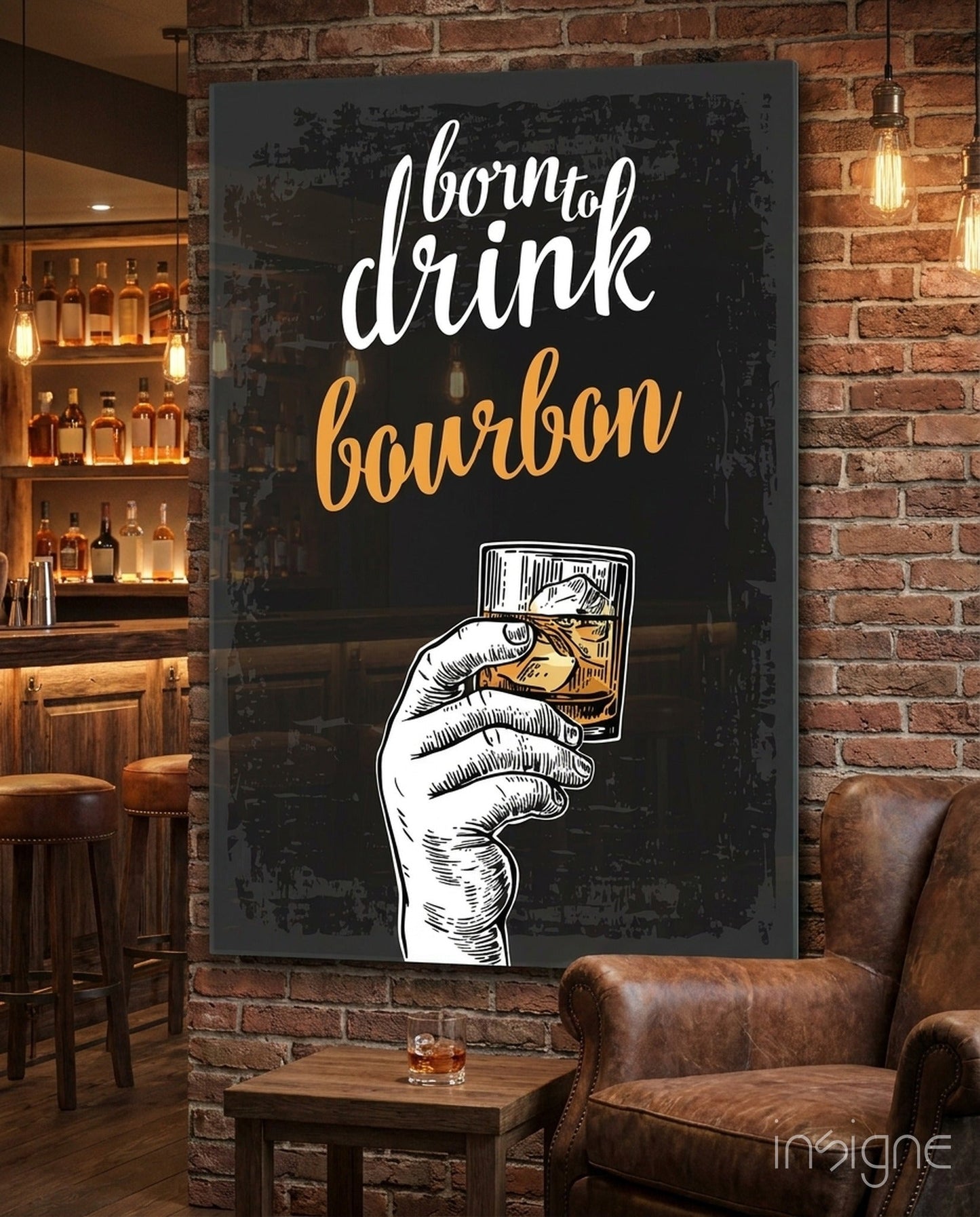 Neon sign displaying "born to drink bourbon" in white and gold lettering with illustrated hand holding whiskey glass, mounted on brick wall above leather chair.