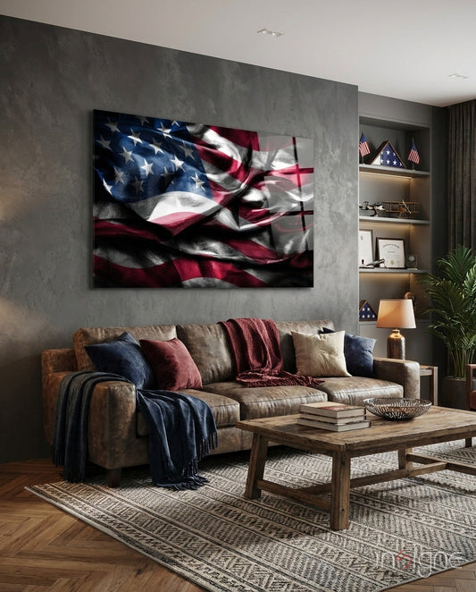 Waving American flag glass wall art in dark tones displayed above brown leather sofa in modern living room with shelving and decor.
