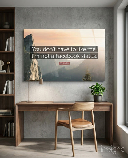 Glass wall art displaying a misty mountain landscape with text reading "You don't have to like me, I'm not a Facebook status" by Wiz Khalifa, mounted above a wooden desk.