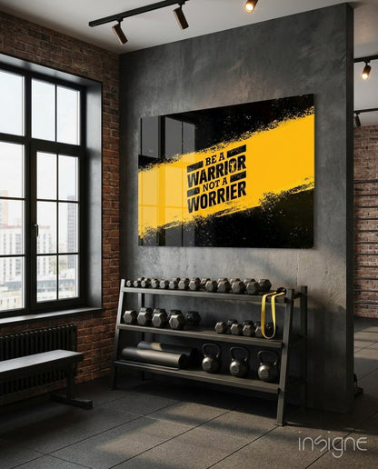 Modern gym interior with yellow and black "Be a Warrior Not a Worrier" glass wall art above dumbbell rack.