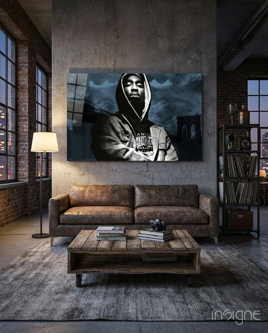 Black and white glass wall art of hooded figure displayed above brown leather couch in industrial loft interior.