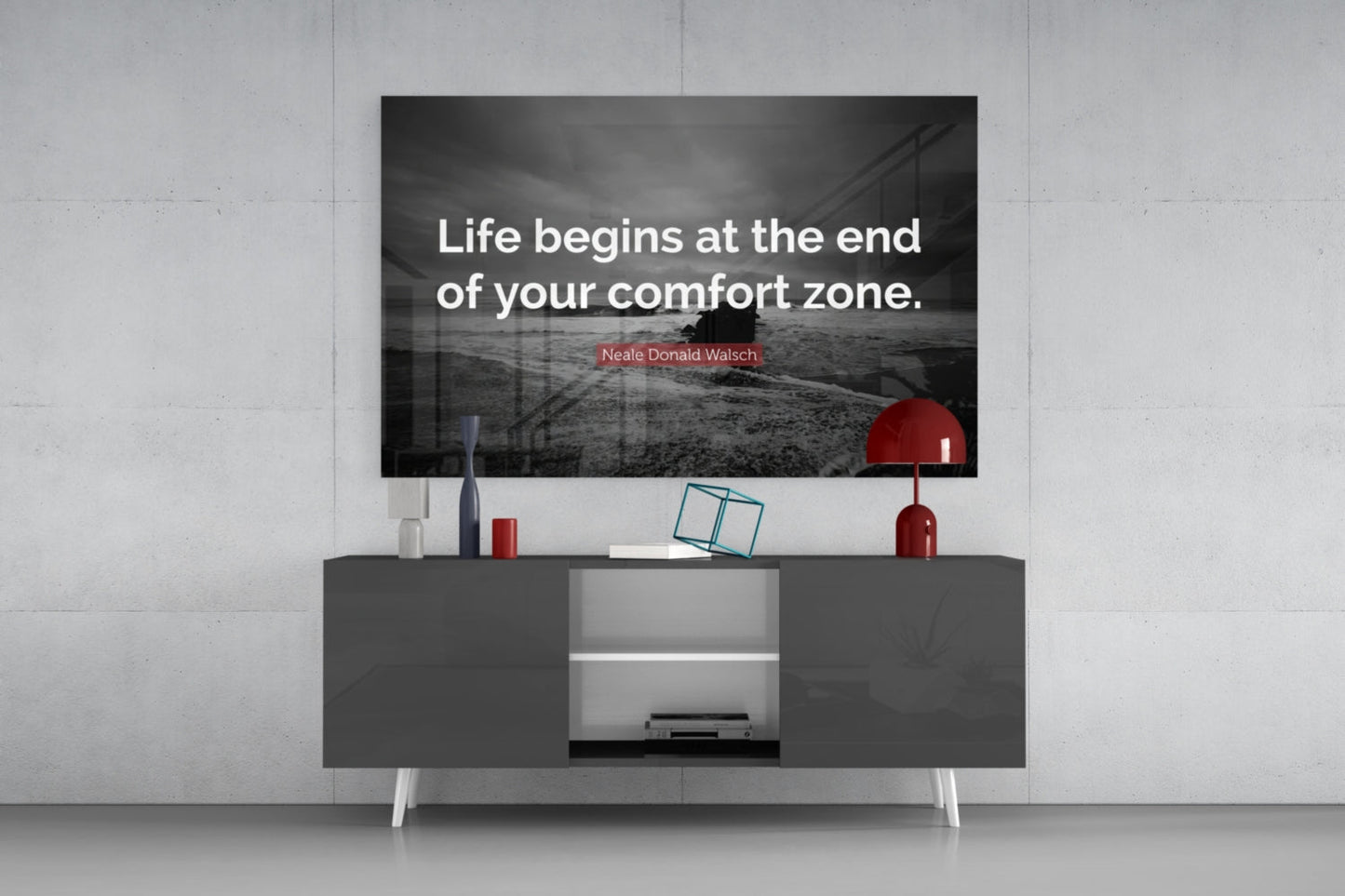 Glass wall art displaying motivational quote "Life begins at the end of your comfort zone" mounted above modern media console.