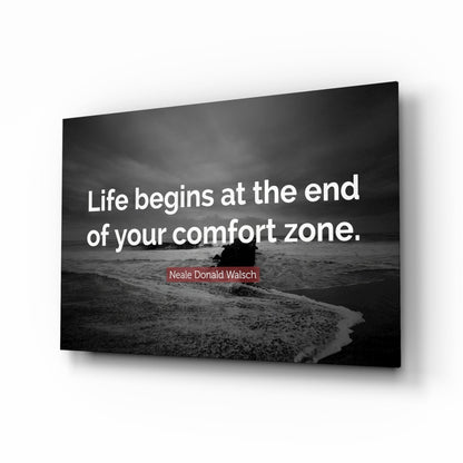 Black and white beach scene with surfer in ocean on glass wall art displaying white text quote by Neale Donald Walsch, angled perspective view.
