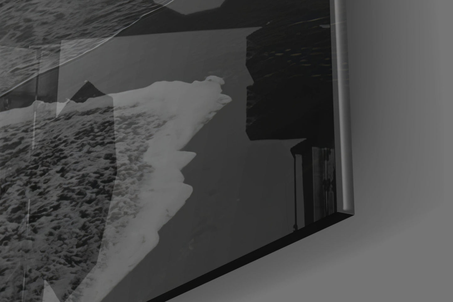 Black and white photograph showing glass wall art installed on white wall, displaying silhouetted profile facing sandy beach landscape through window.