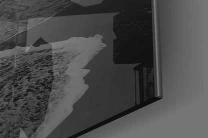 Black and white photograph showing glass wall art installed on white wall, displaying silhouetted profile facing sandy beach landscape through window.