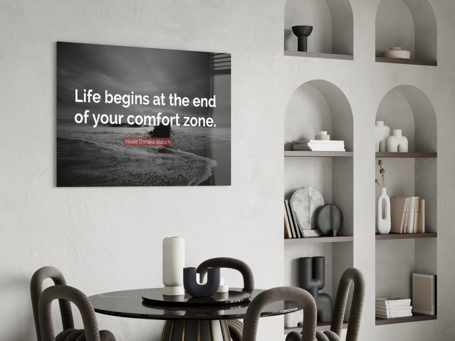 Modern dining room with black glass wall art displaying Neale Donald Walsch quote above round table and chairs.