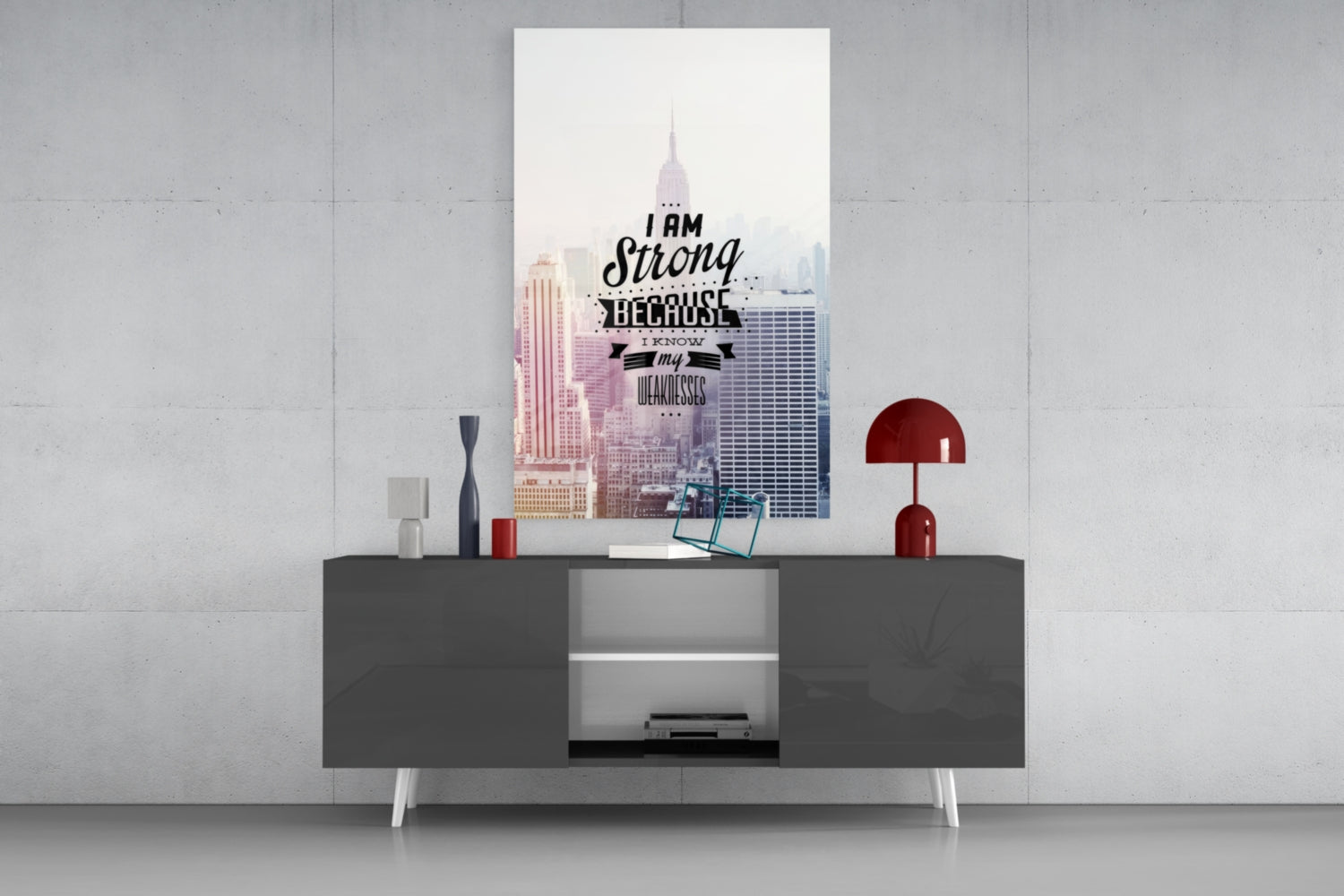 Modern living room setting displaying motivational glass wall art above gray media console with red lamp and decorative accessories.