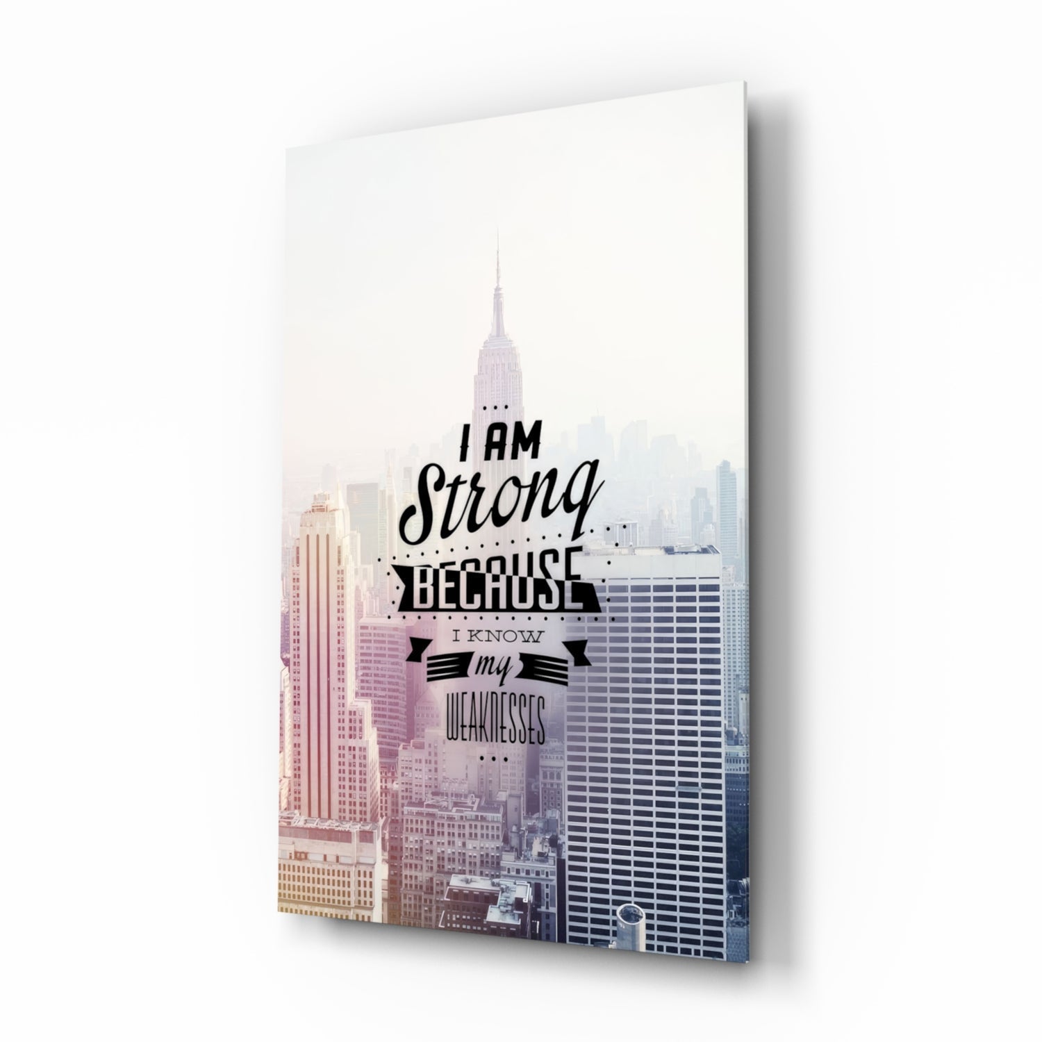 Glass wall art panel displaying New York City skyline with motivational text "I am Strong Because I Know my Weaknesses" in black lettering.
