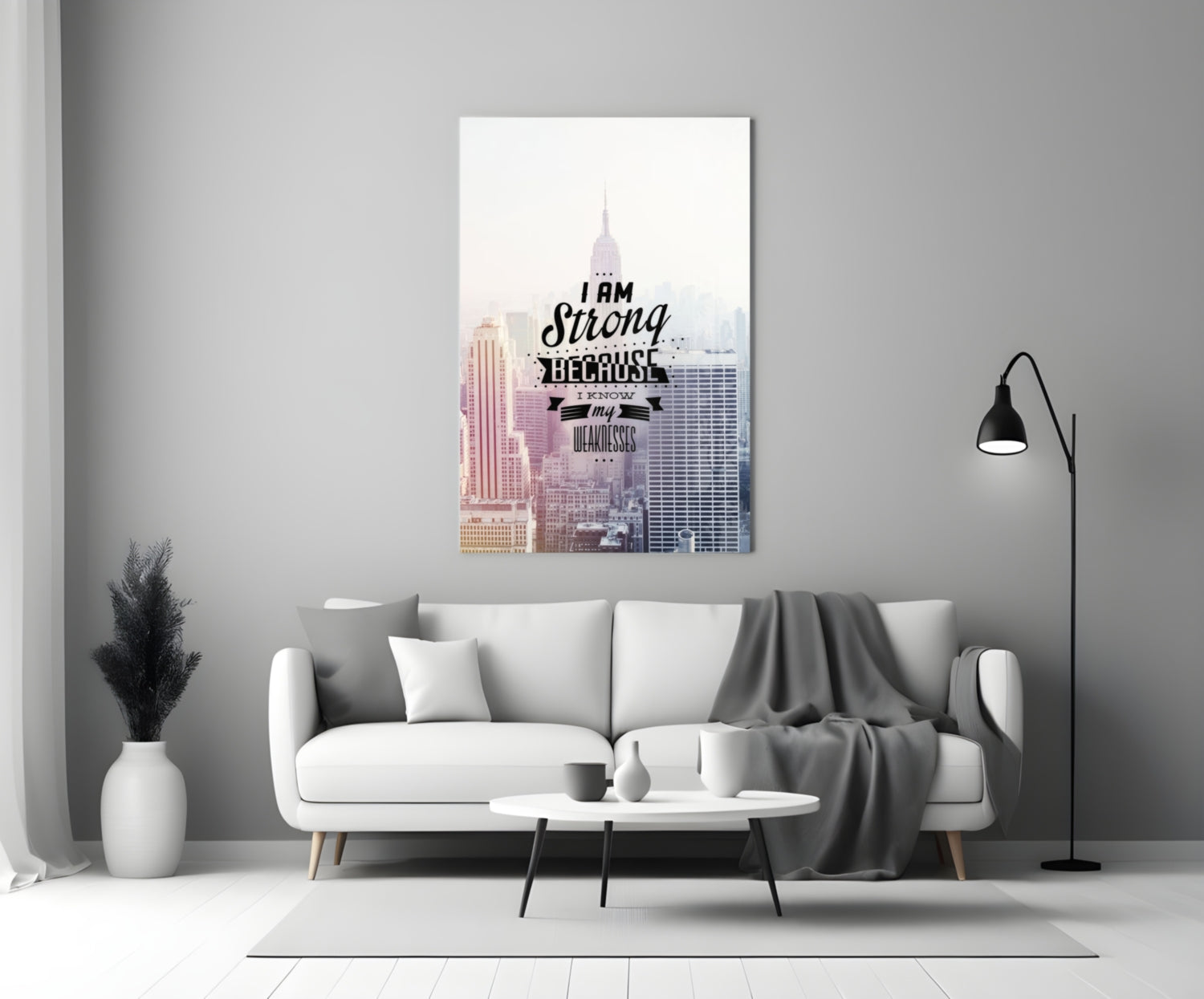 Motivational glass wall art featuring a cityscape with "I am Strong Because I Know my Weaknesses" text displayed above a modern white sofa.