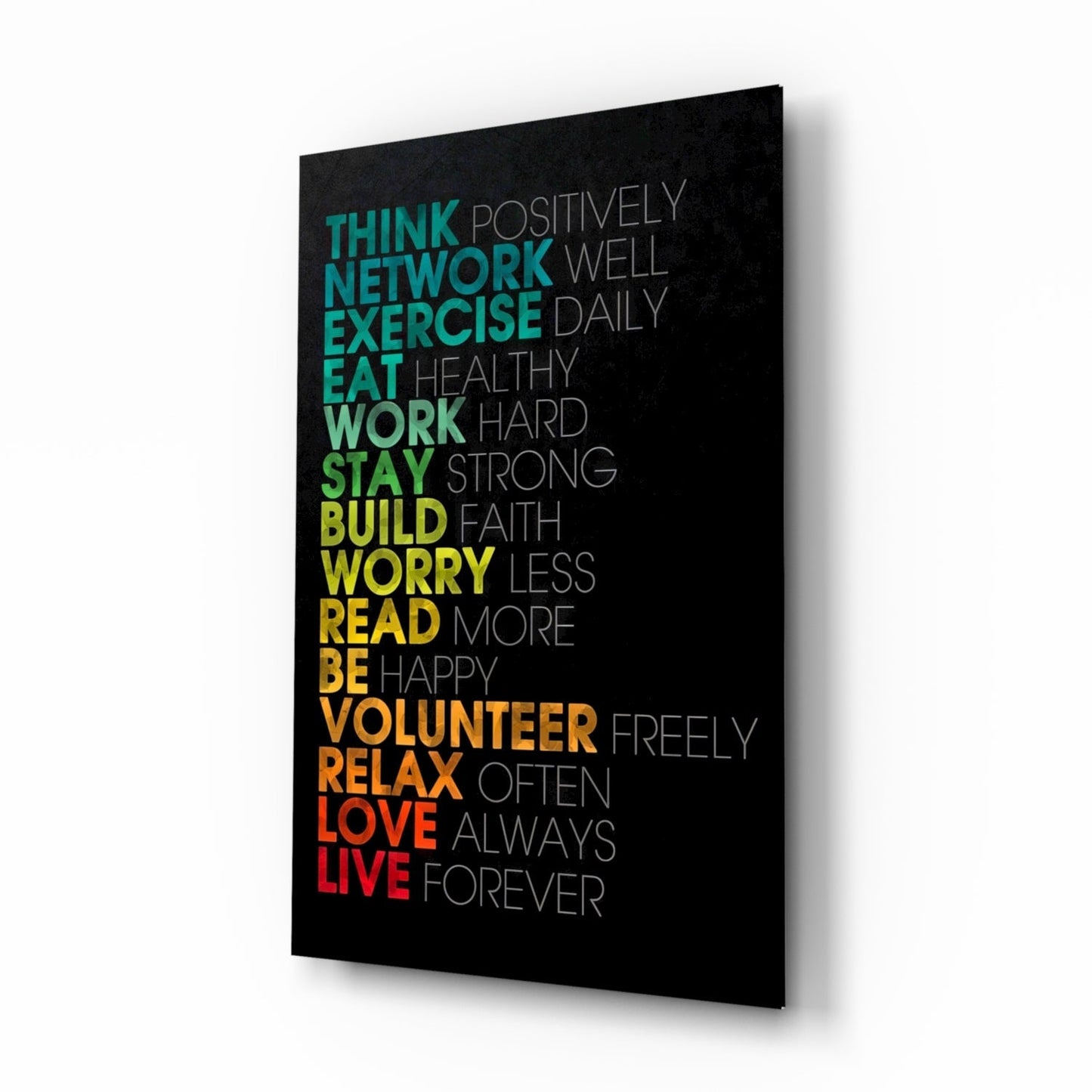 Black glass wall art panel with colorful gradient text listing life advice phrases from "Think" to "Live," photographed at an angle showing depth and shadow.