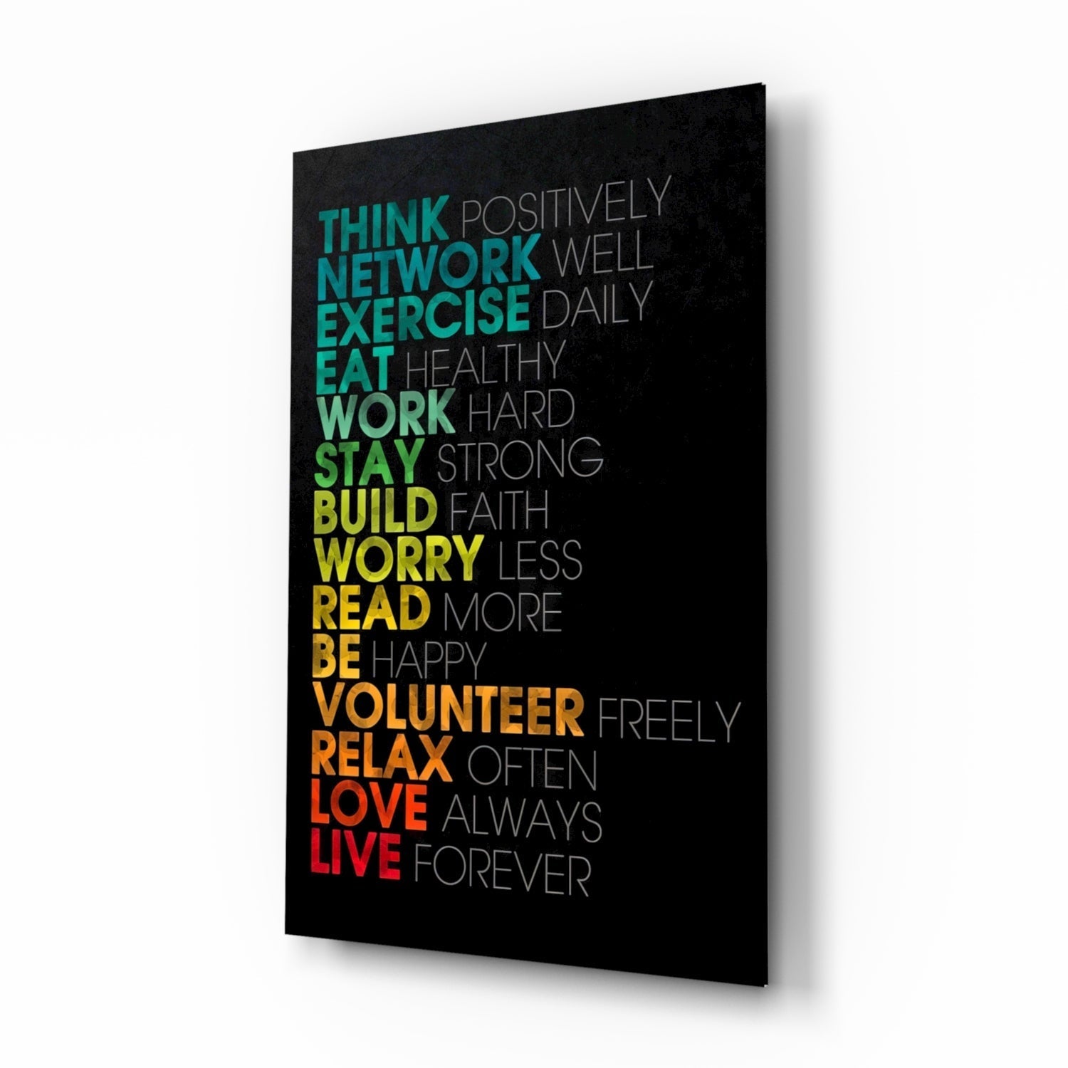 Black glass wall art panel with colorful gradient text listing life advice phrases from "Think" to "Live," photographed at an angle showing depth and shadow.