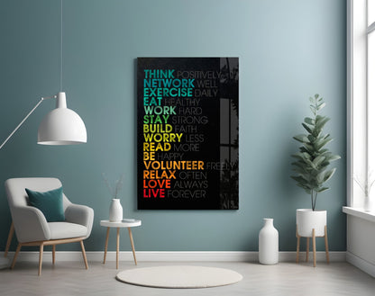 Modern living room with turquoise walls displaying colorful motivational glass wall art with life advice phrases in gradient text on black background.