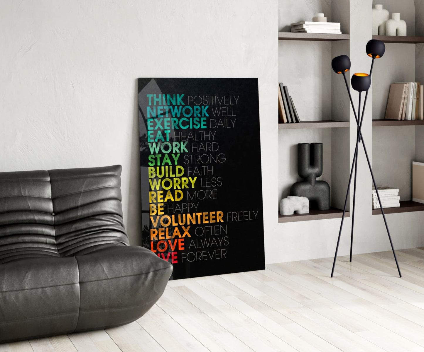 Black glass motivational wall art with colorful gradient text displaying life advice phrases leaning against white wall in modern living room setting.