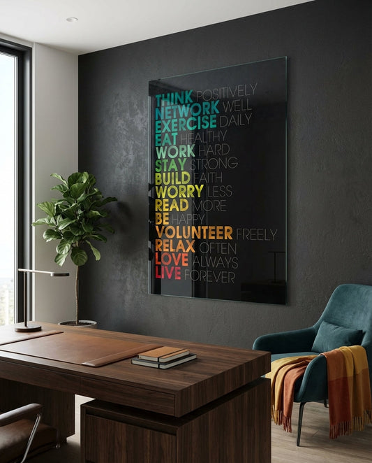 Modern office workspace featuring a colorful motivational glass wall art with rainbow text on dark background above wooden desk.