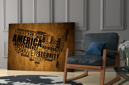 Brown wooden USA map wall art with black patriotic text displayed in a modern room beside a wooden chair with blue cushions.