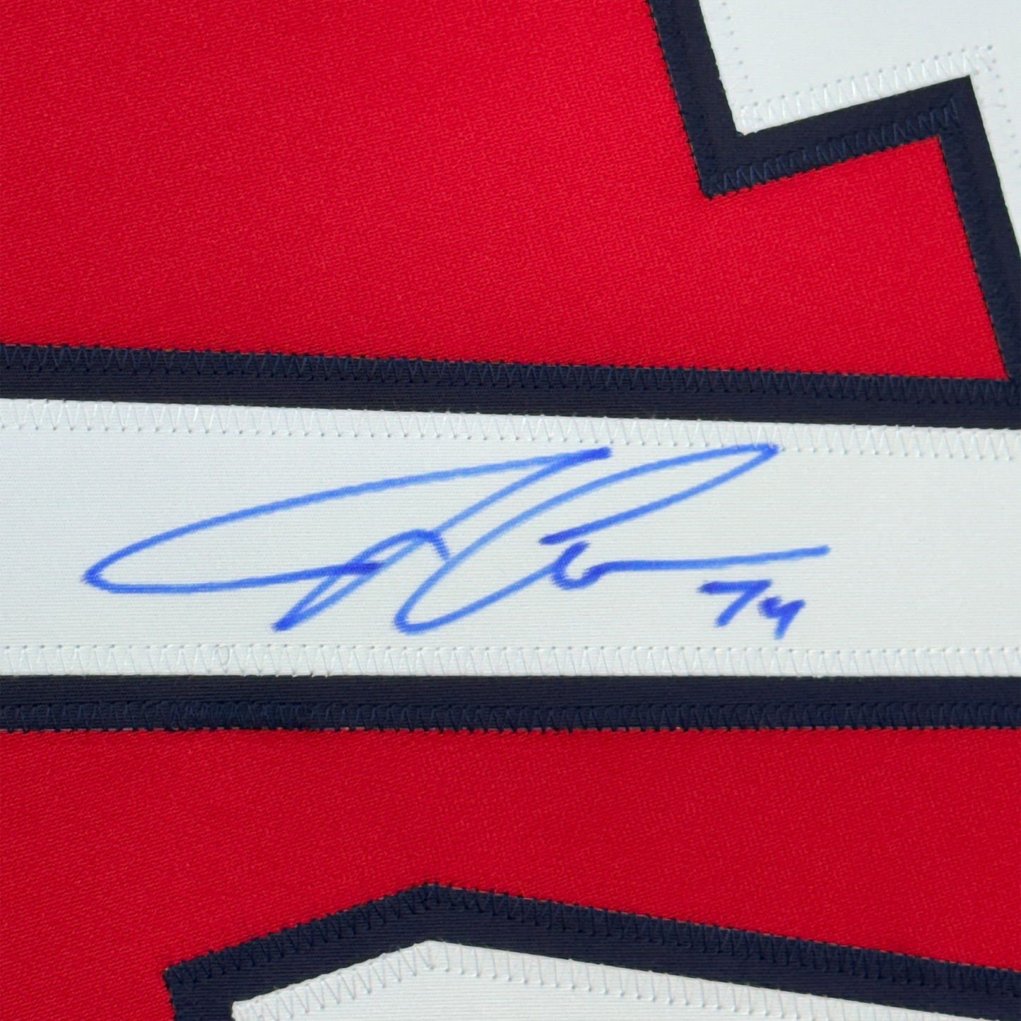 Close-up of blue autograph signature on white stripe of red, white, and navy hockey jersey.