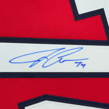 Close-up of blue autograph signature on white stripe of red, white, and navy hockey jersey.